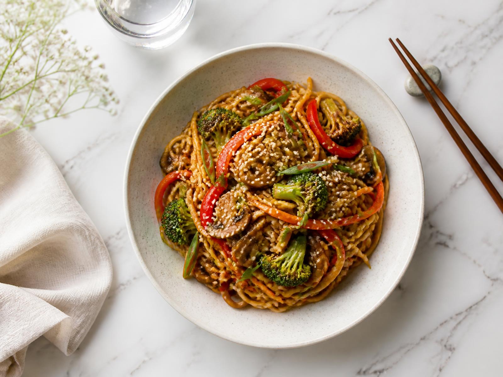 Plato de fideos salteados con verduras sobre mármol